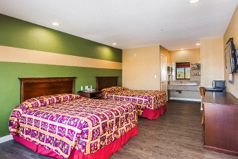 Room with two queen beds and a television with sink in the back